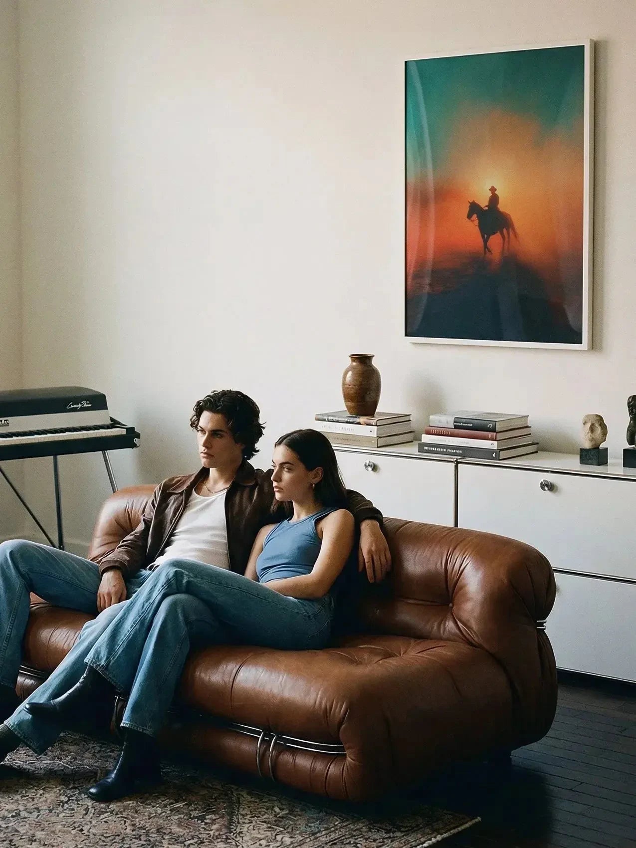 Framed cowboy poster with sunset colors in a modern living room above brown leather sofa