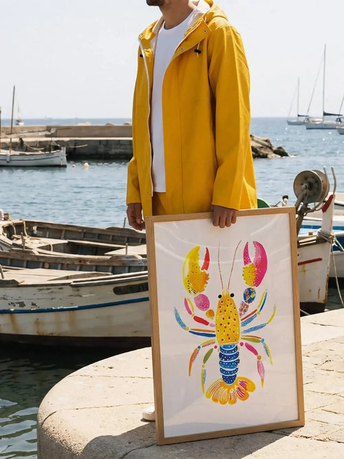 Colorful lobster art poster held by person in yellow jacket at marina with boats