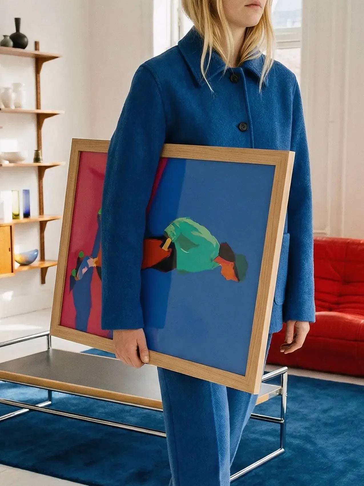 Woman in blue coat holding colorful abstract roller skating art poster in frame